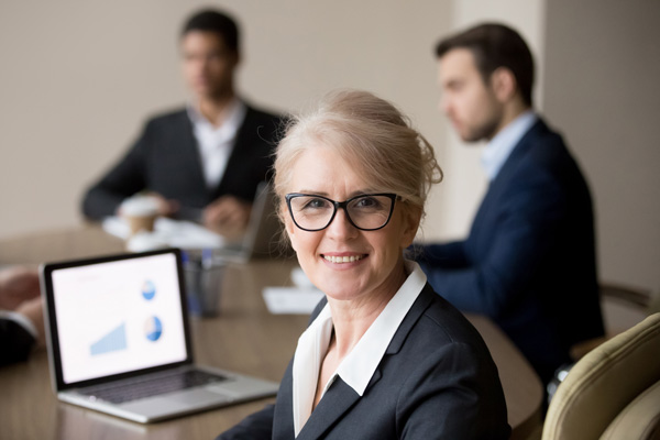 An older woman sitting at a boardroom table.
